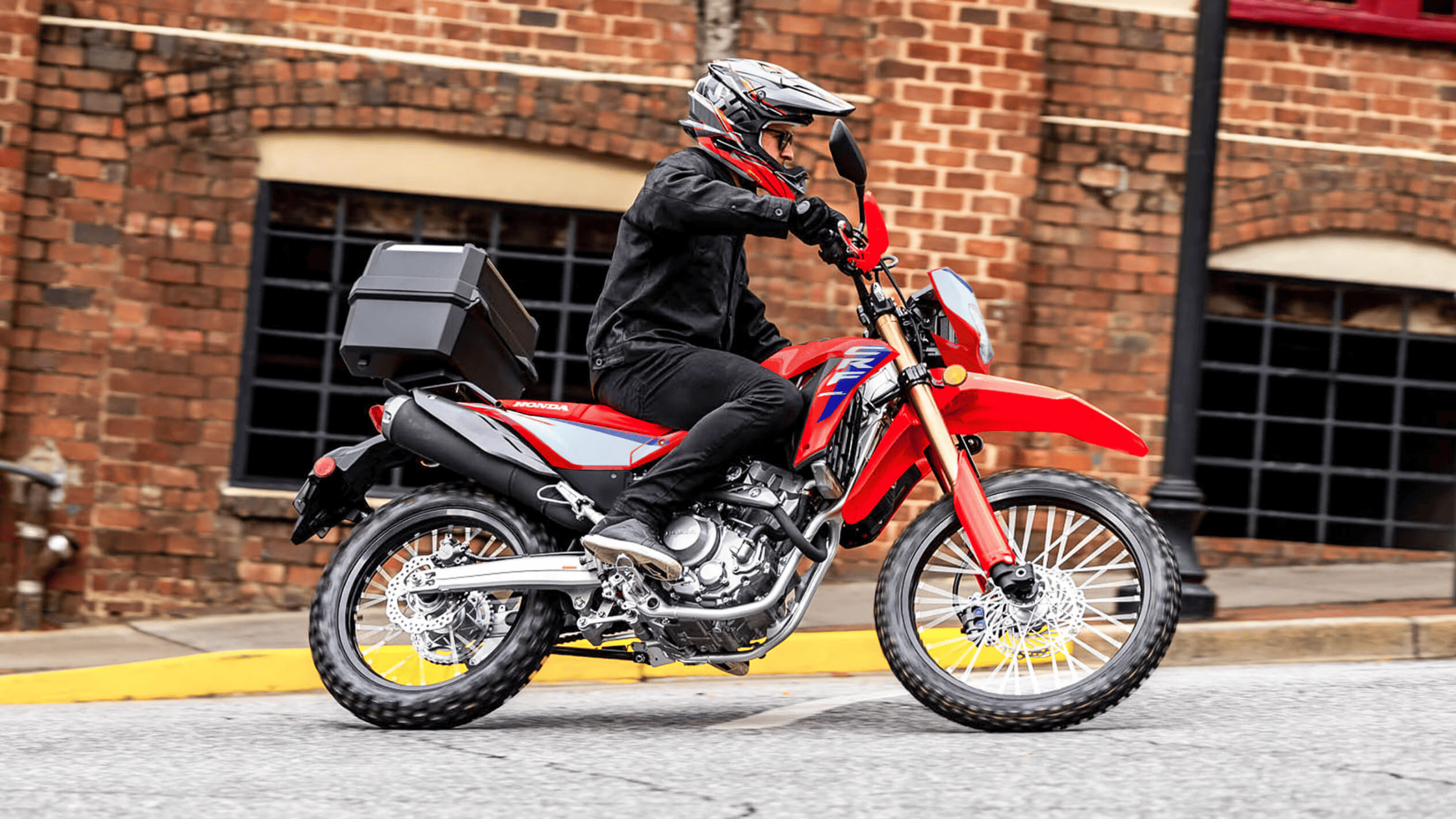 Rider on red Honda CRF300L ABS motorcycle, urban street setting, side view exterior