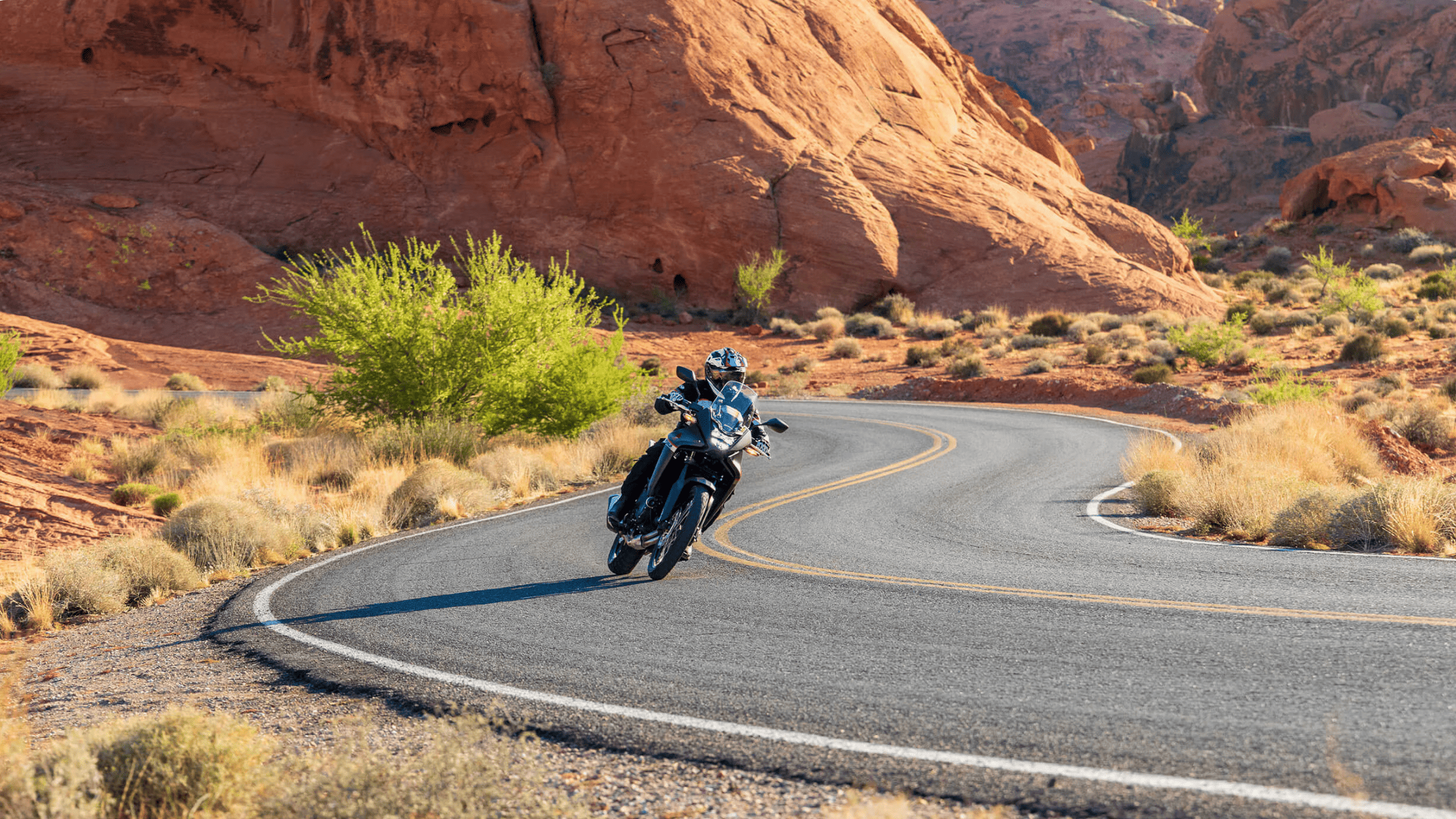 2025 Honda Transalp navigating winding desert canyon road with rocky red landscape around it