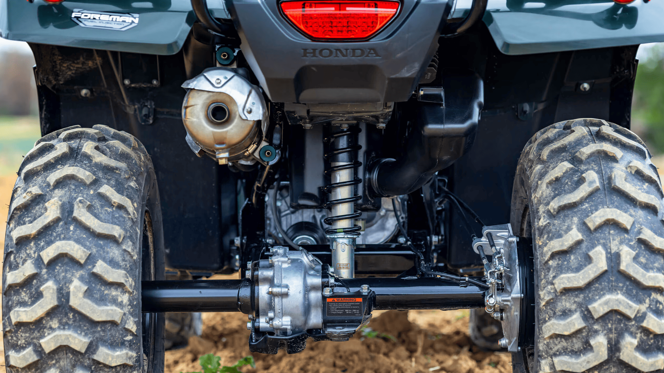 Rider navigating forest trail on 2025 Honda FourTrax Foreman 4x4 ATV with cargo storage on front and rear racks
